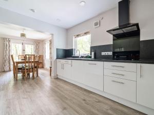 uma cozinha com armários brancos e uma mesa com cadeiras em Cherry - Woodland Cottages em Bowness-on-Windermere