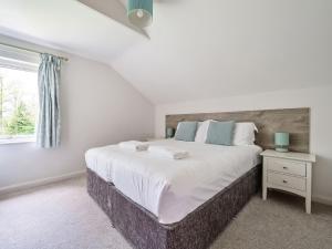 um quarto com uma cama grande e uma janela em Cherry - Woodland Cottages em Bowness-on-Windermere