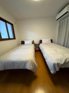 dos camas sentadas una al lado de la otra en un dormitorio en Guesthouse Atelier Ten 民泊アトリエ天, en Osaka