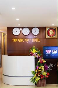 - un hall d'accueil avec des horloges murales et des fleurs dans l'établissement Tam Giác Mạch Hotel, à Ha Giang