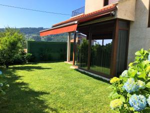 a house with a yard with green grass and flowers at Casa moderna para 10 en Sanxenxo cerca de la playa in Sanxenxo