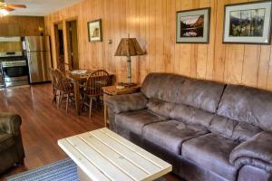 Una sala de estar con un sofá de cuero y una mesa. en Nitschke's Resort Cabin #15, en Minocqua