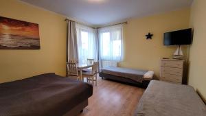 a bedroom with two beds and a desk and a television at Amber in Mrzeżyno