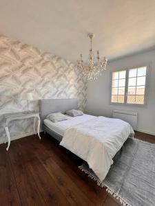 - une chambre avec un grand lit et un lustre dans l'établissement La Villa verdoyante, à Baillargues