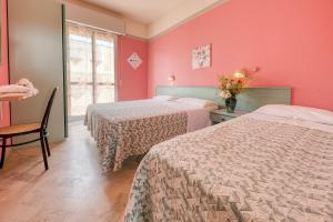 Duas camas num quarto com paredes cor-de-rosa em Hotel Sabbia d'Oro em Rimini