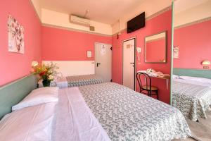 2 letti in una camera con pareti rosse di Hotel Sabbia d'Oro a Rimini