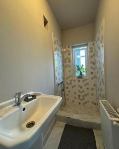 La salle de bains blanche est pourvue d'un lavabo et d'une fenêtre. dans l'établissement Serbian House, à Timişoara