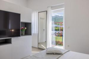 Una habitación blanca con un televisor y una puerta corrediza de vidrio. en Villa Culin, en Dugopolje 30 fotos más