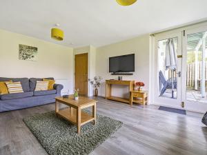a living room with a couch and a tv at Rowan - Woodland Cottages in Bowness-on-Windermere