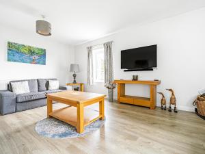 een woonkamer met een bank en een tv bij Beech - Woodland Cottages in Bowness-on-Windermere