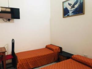 Habitación con 2 camas de color naranja y TV. en Hotel Piamonte en Buenos Aires