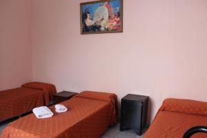 Cette chambre comprend deux lits et un tableau mural. dans l'établissement Hotel Piamonte, à Buenos Aires
