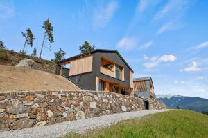 a house on a hill with a stone wall at NEUERÖFFNUNG 'Zoler Chalets' mit Panorama Sauna in Feldthurns