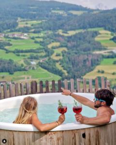 Ein Mann und eine Frau in einer Badewanne mit Weingläsern. in der Unterkunft Hotel Residence Gasser in Villanders