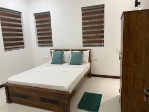 a bedroom with a bed with blue pillows and windows at Silina Airport Residence in Katunayaka