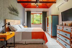 1 dormitorio con 1 cama, escritorio y TV en Casa de campo Secretário/ Pedro do Rio RJ, en Petrópolis
