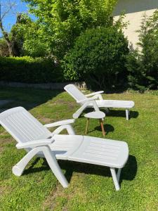 dos sillones blancos y un banco en el césped en Maison T3 près de Toulouse, en Frouzins