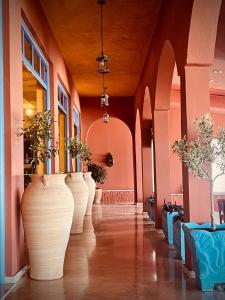 un couloir avec de grands vases avec des plantes dans l'établissement Hotel Coral Beach, à Roda