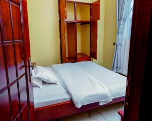 a bedroom with a bed and a wooden cabinet at Orchard apartment in Mutungo