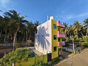 本地治里的住宿－Gratitude Retreat，棕榈树的黄色粉红色建筑