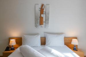 a bed with white pillows and a clock on the wall at Hotel Sachsenklemme in Fortezza