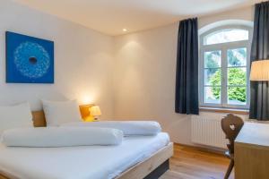 a bedroom with two beds and a desk and a window at Hotel Sachsenklemme in Fortezza