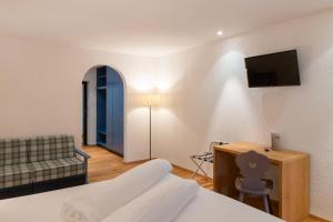 a bedroom with a bed and a couch and a television at Hotel Sachsenklemme in Fortezza