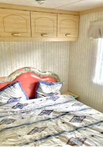 a bed with a red headboard in a bedroom at Cosy Mobilhome in La Baule