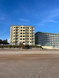 un gran edificio blanco en la playa junto a un edificio en Royal Floridian Resort South by Spinnaker en Ormond Beach