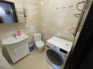 bagno con lavandino e servizi igienici e lavatrice. di Затишна квартира для Вашої родини a Vinnycja