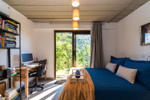 a bedroom with a blue bed and a desk and a window at Santa Serra Itaipava in Itaipava