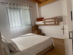 a white bedroom with a bed and a window at Guest-Room Zoi&Teri in Tepelenë