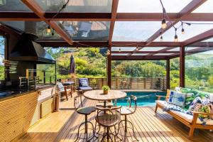 a deck with a table and chairs and a pool at Santa Serra Itaipava in Itaipava