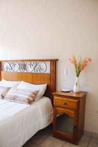 un letto con un tavolo e un vaso di fiori sopra di Acacia a Mendoza