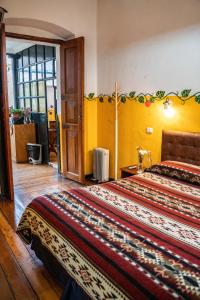 a bedroom with a large bed with yellow walls at Hostal Riviera Sucre in Otavalo