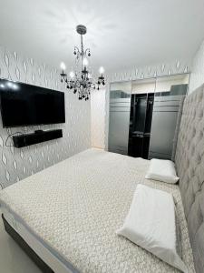 1 dormitorio con 1 cama con TV y lámpara de araña en Departamento Deluxe en Piura