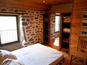 een slaapkamer met een bed en een stenen muur bij Maison au Giraldès Le Claux Puy Mary Volcan chalet in Le Claux