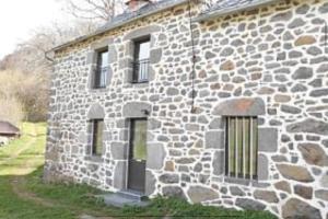 een stenen gebouw met ramen en een deur bij Maison au Giraldès Le Claux Puy Mary Volcan chalet in Le Claux