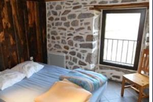 een bed in een kamer met een stenen muur bij Maison au Giraldès Le Claux Puy Mary Volcan chalet in Le Claux