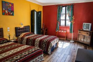 two beds in a room with red and yellow walls at Hostal Riviera Sucre in Otavalo