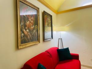 un sofá rojo en una habitación con pinturas en la pared en Colosseum-Apartments en Roma