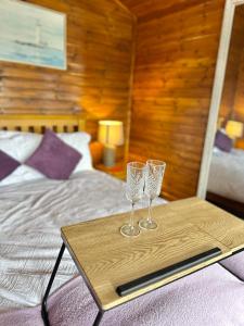 two wine glasses on a wooden tray on a bed at Cosy Portmor Log Cabin in Malin Head
