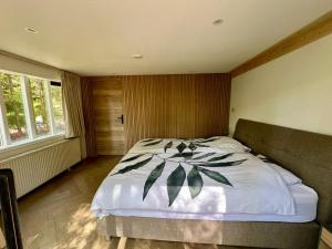 a bedroom with a large bed with white sheets at Kindvriendelijk sfeervol vakantiehuis Bosgeneugte bij zwembad op de Veluwe in Doornspijk