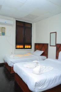una camera con due letti con lenzuola bianche e una finestra di Mina Alsalam Hotel فندق ميناء السلام a Il Cairo