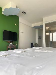 1 dormitorio con 1 cama blanca y TV de pantalla plana en 波斯卡朵民宿, en Magong