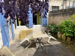 une table et un banc devant une porte bleue dans l'établissement Maison de l horloge, à Avallon