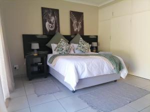 een slaapkamer met een bed met witte lakens en kussens bij Hhusha Hhusha in Malelane