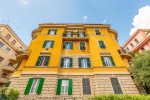 a tall yellow building with green windows at ANDENIS TIBER HOUSE in Rome