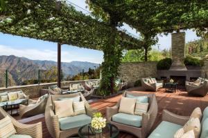 a patio with chairs and a fireplace with mountains in the background at JW Marriott Mussoorie Walnut Grove Resort & Spa in Mussoorie
