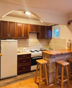 a kitchen with wooden cabinets and a stove and stools at Apartman Olivera in Žabljak